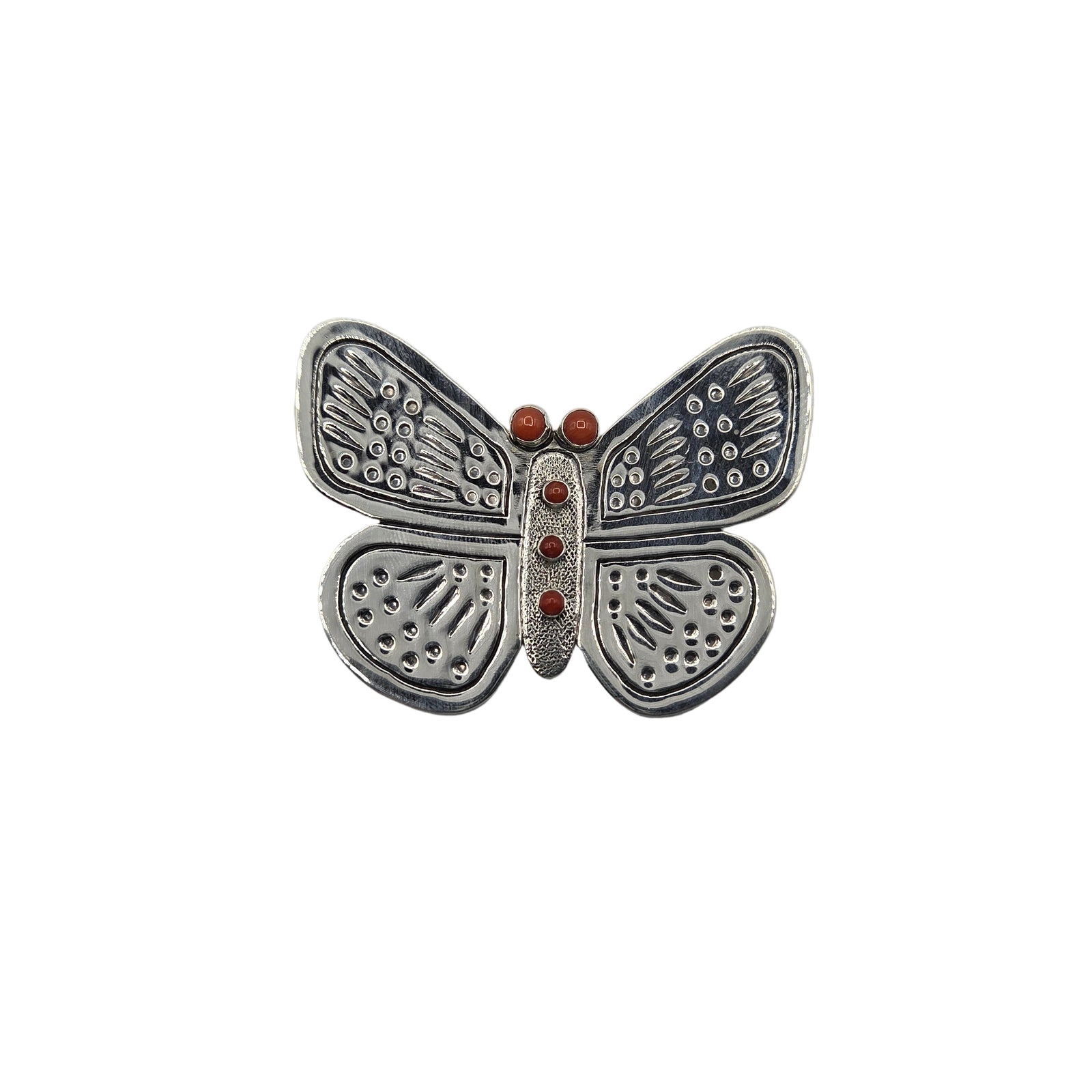 Silver butterfly-shaped brooch with red stones on a white background