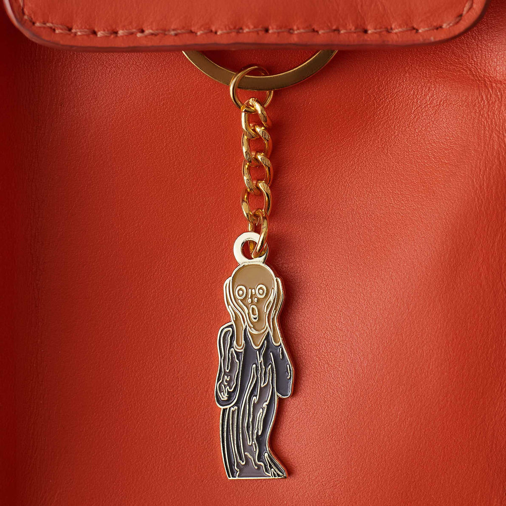 Keychain with Munch&#39;s The Scream on a red leather surface