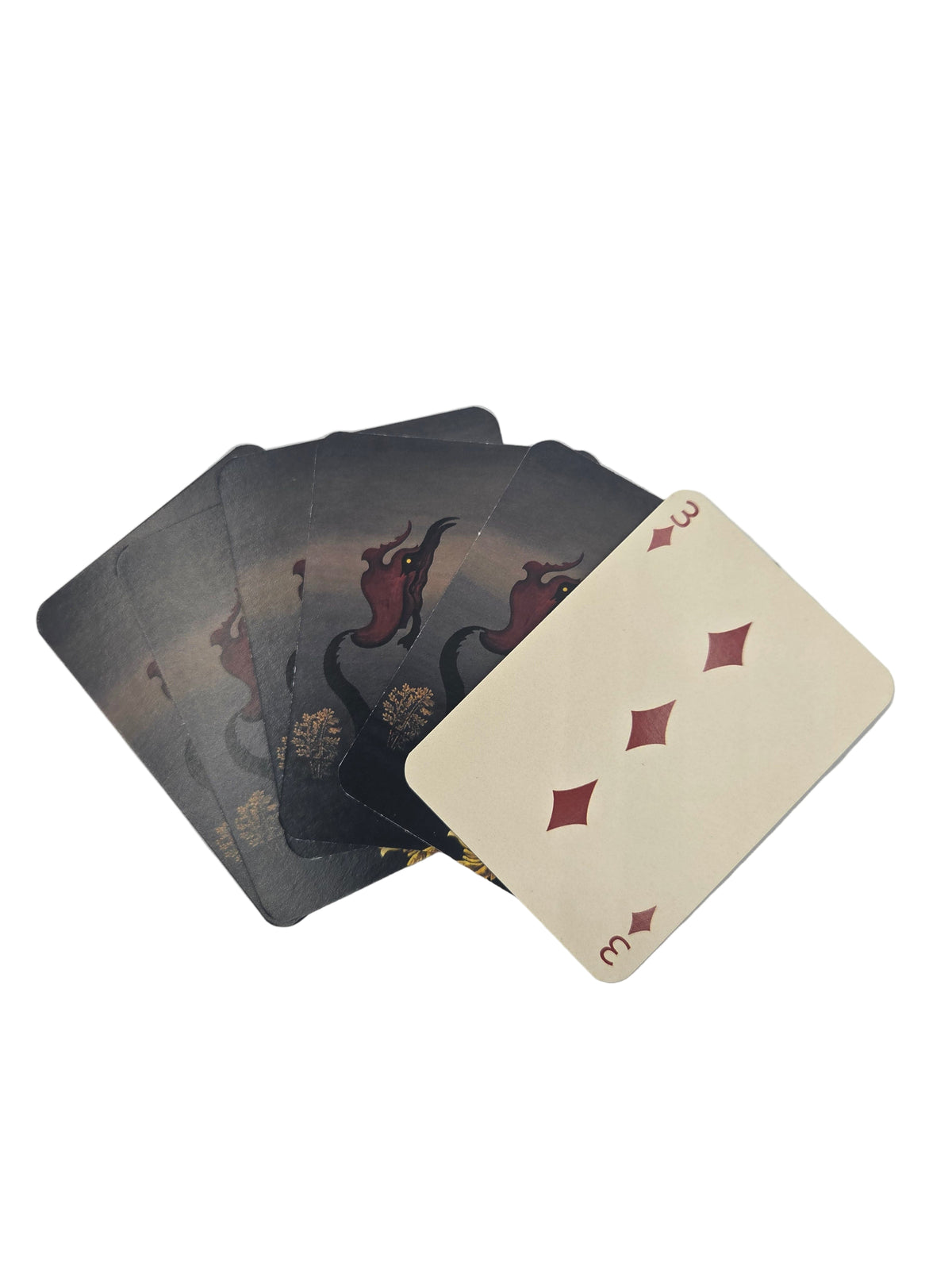 Playing cards with a three of diamonds card on top of a stack on a light gray background