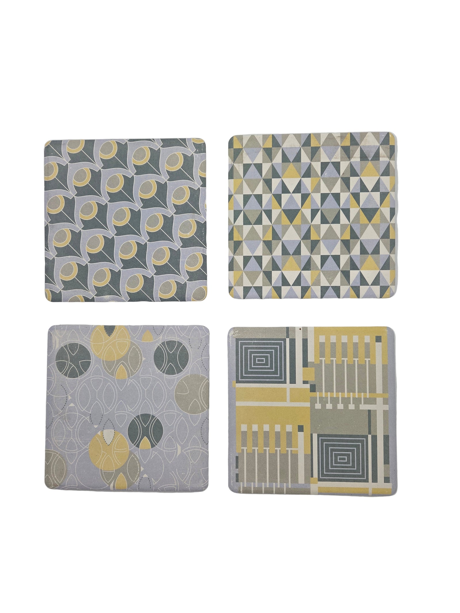Four geometric patterned coasters on a white background