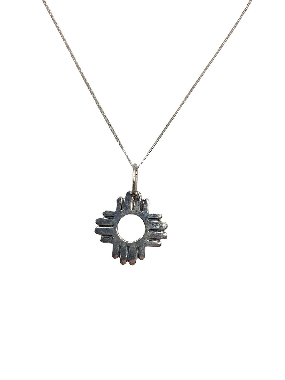 Silver necklace with a sunburst pendant on a light gray background