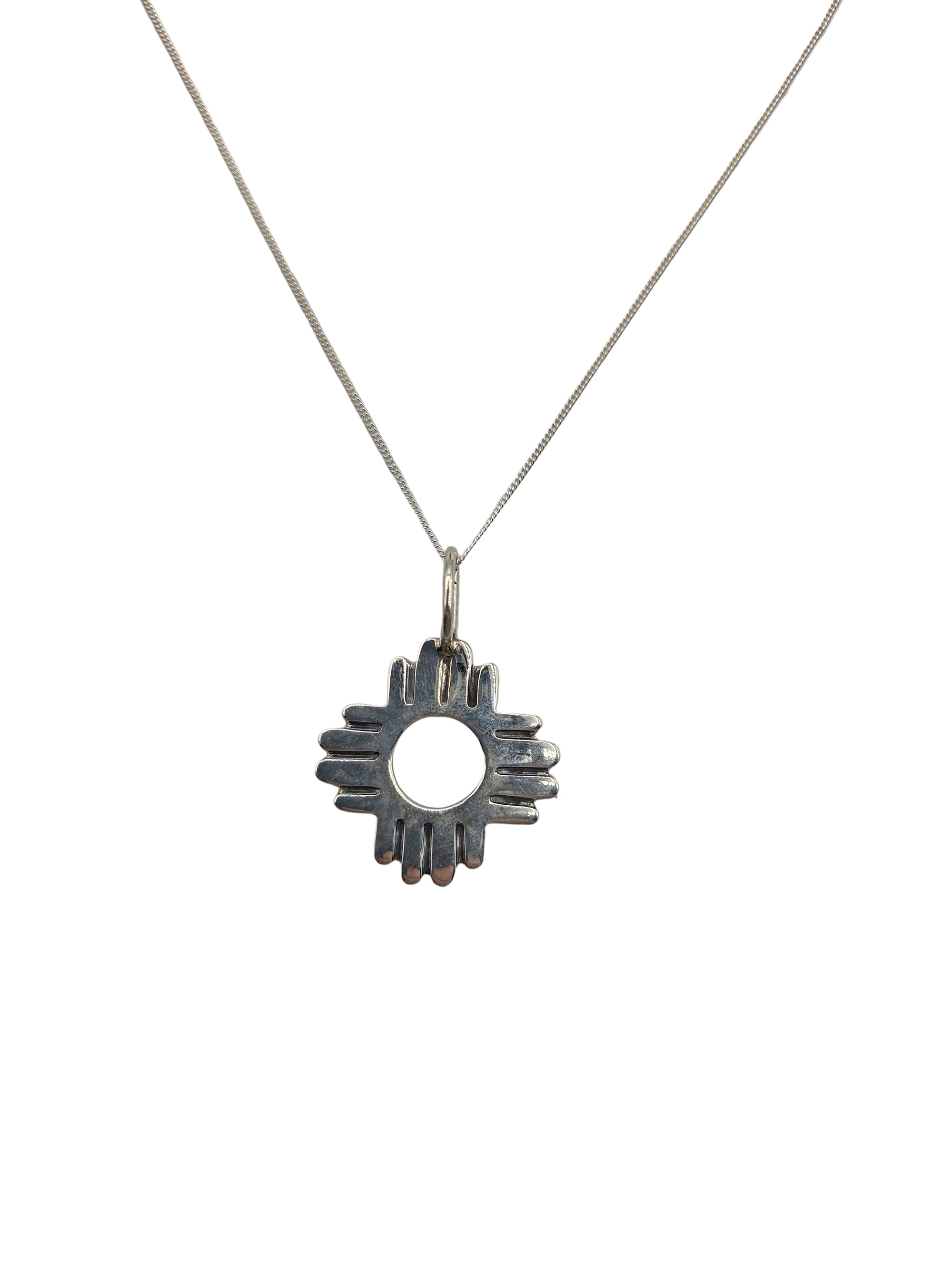 Silver necklace with a sunburst pendant on a light gray background