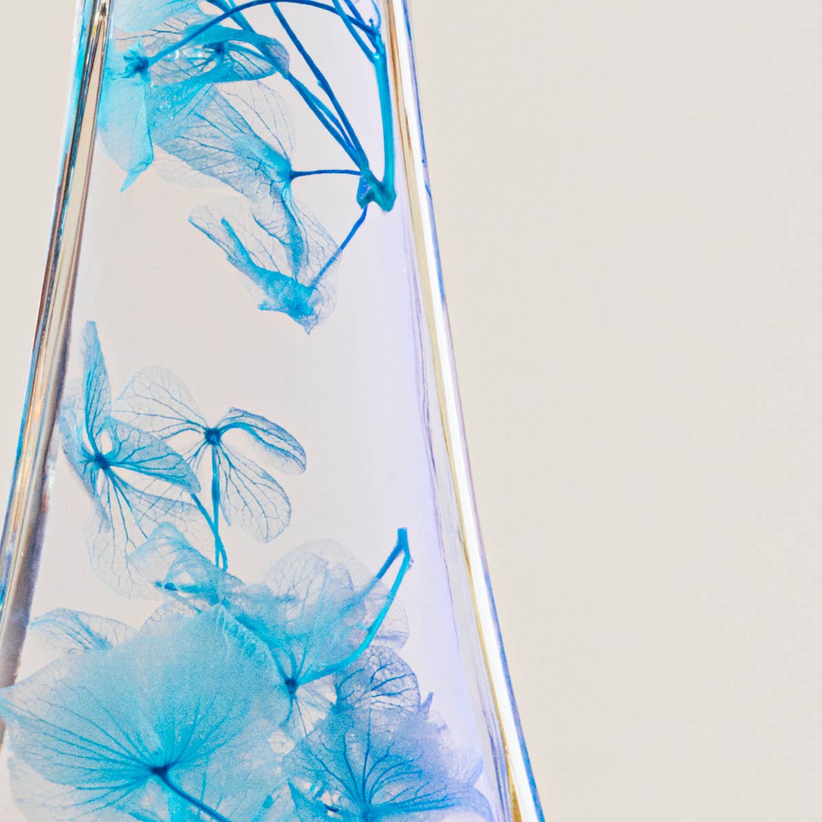 Clear glass vase with blue floral design on a light gray background