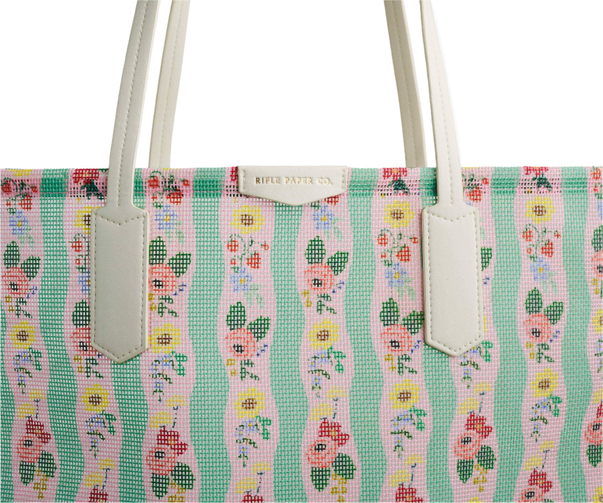 Floral patterned handbag with white handles on a white background with Rifle Paper Co branding