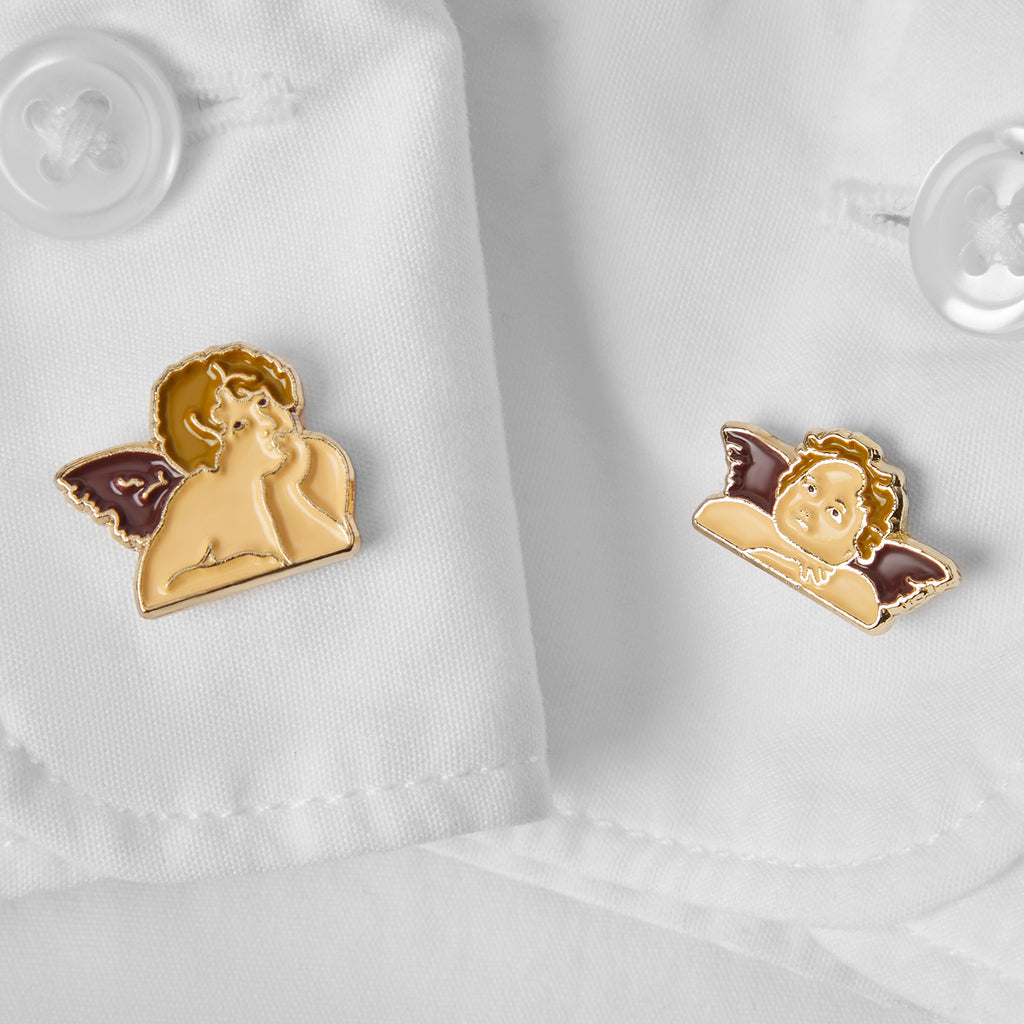 Two angel pins on a white shirt background