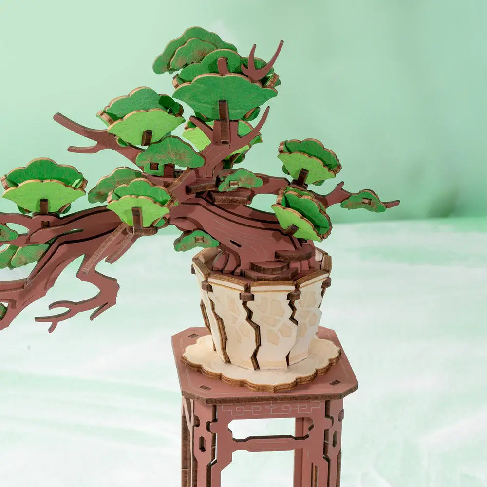 Wooden bonsai tree model on a stand with a light green background