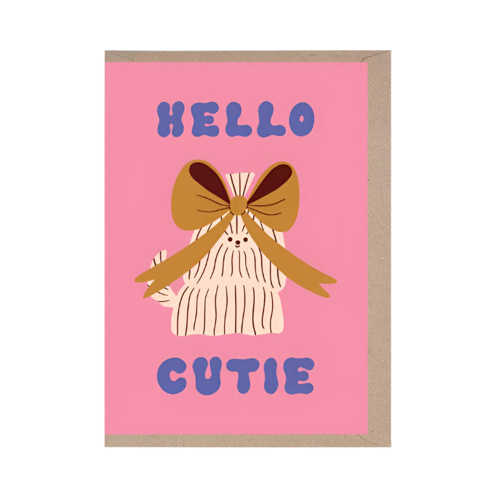 Greeting card with a white dog with a large bow in it's hair and 'Hello Cutie' text on a pink background