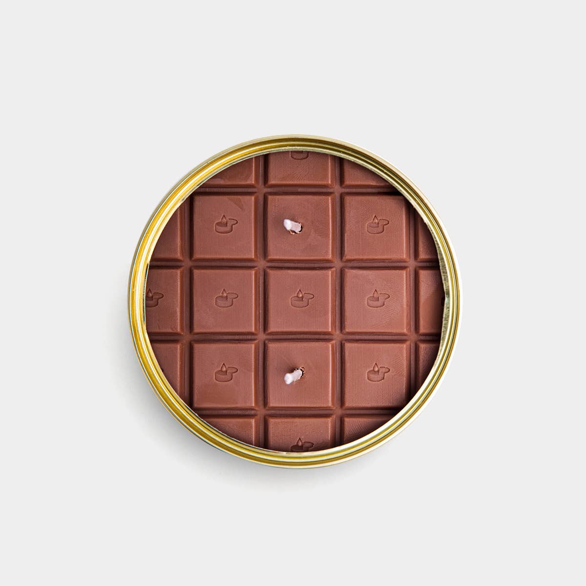 Chocolate bar candle in a gold tin on a light gray background