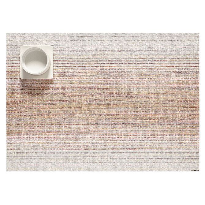 Textured placemat with orange and reds with a bowl on a white background
