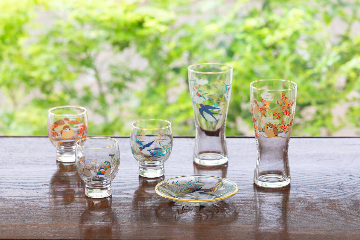 Set of decorative glass tumblers on a wooden surface with a blurred natural background