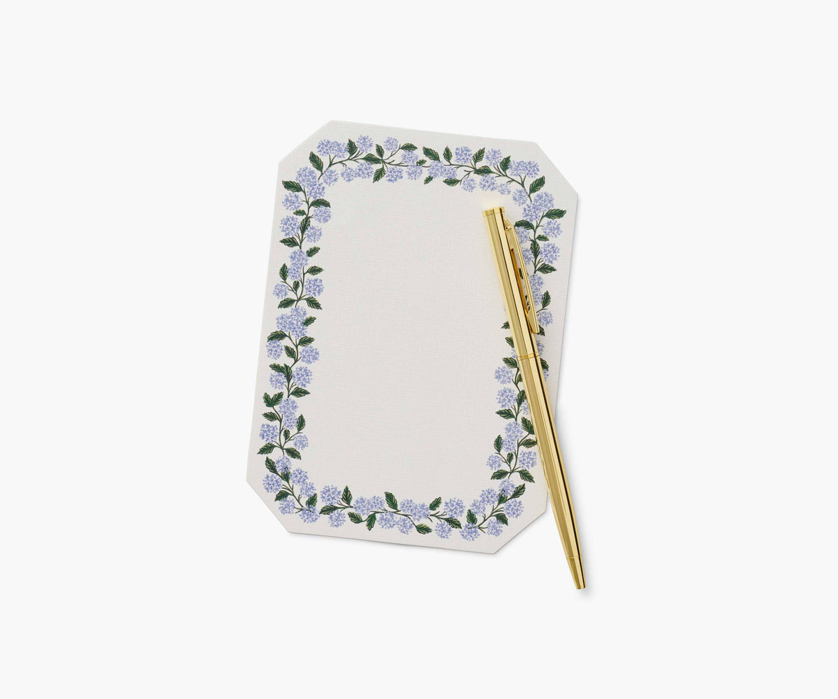 Floral border note pad with a gold pen on a white background
