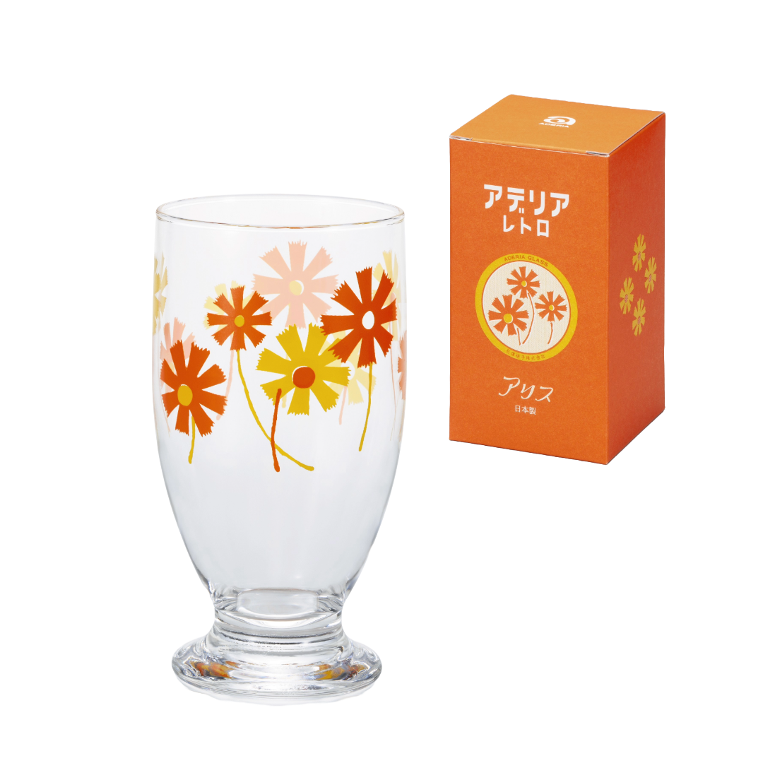 Clear glass with orange floral design next to its packaging on a white background