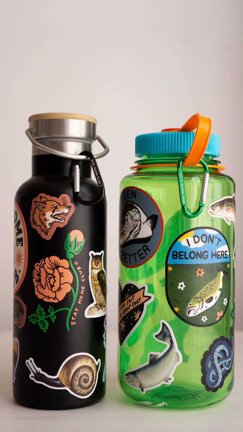 Black water bottle with colorful stickers and green water bottle with stickers on a light gray background