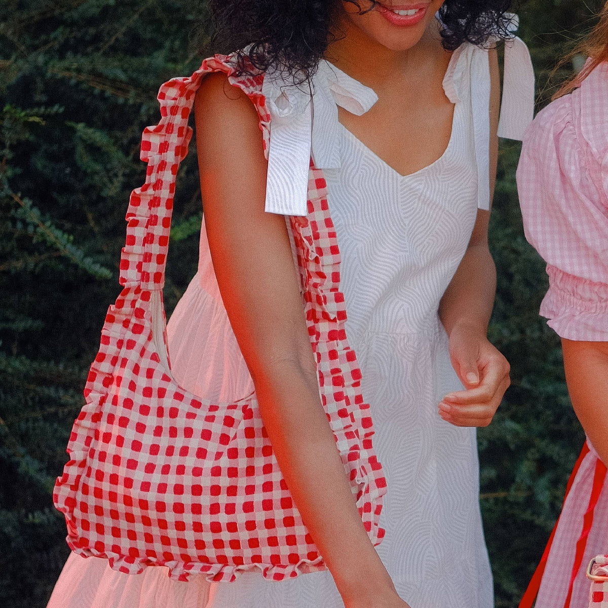 Person wearing a white dress with a red and white checkered bag