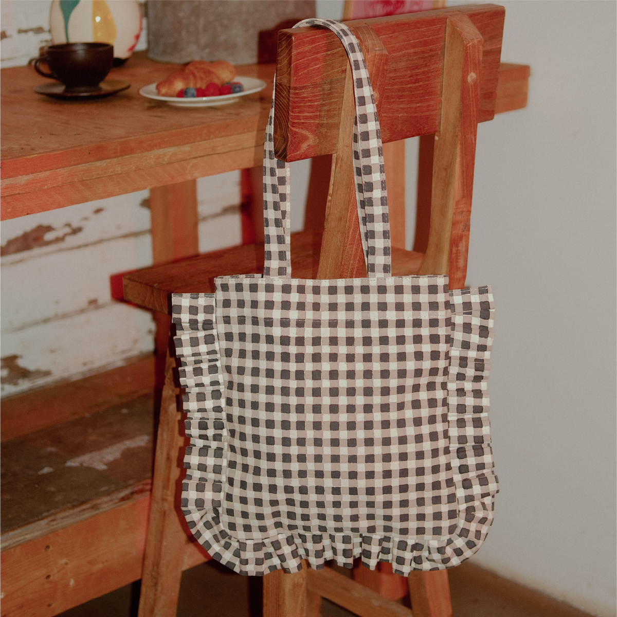 Black and white checkered bag hanging on a wooden chair with a blurred background