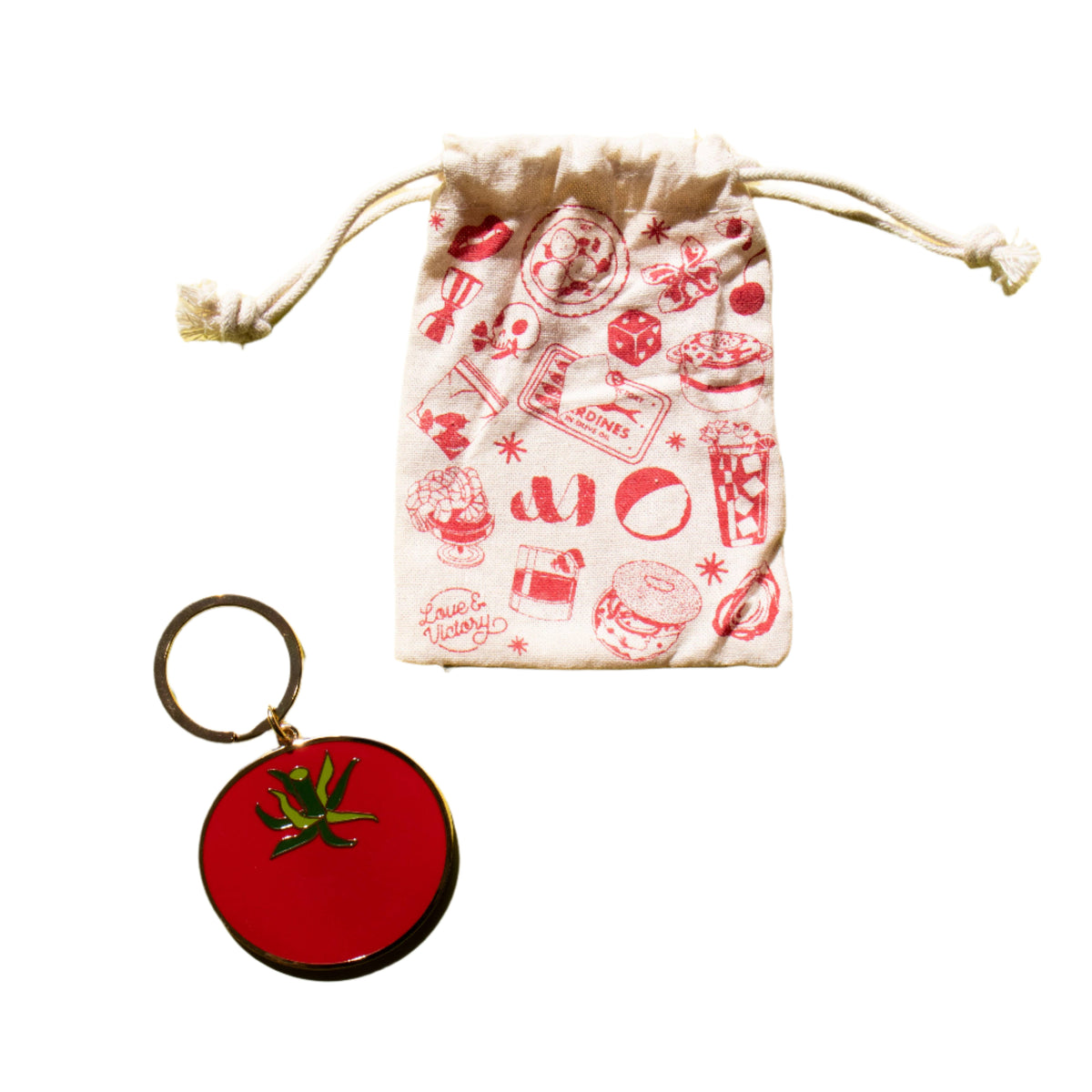Red keychain with a tomato design next to a drawstring bag
