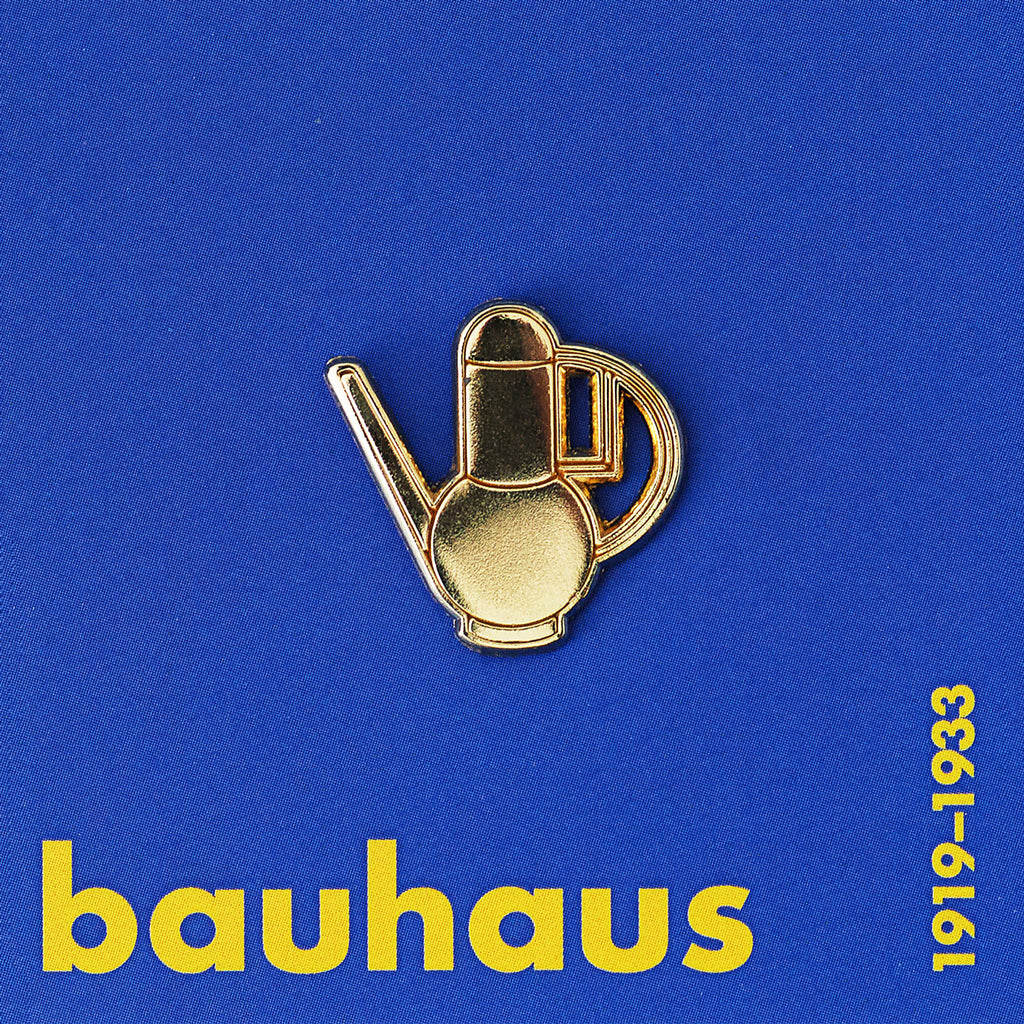 Gold-colored teapot-shaped object on a blue background with &#39;bauhaus&#39; text.