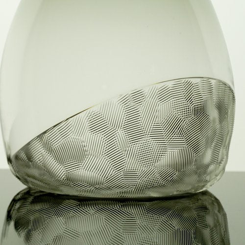 Glass vase with textured design on a reflective surface