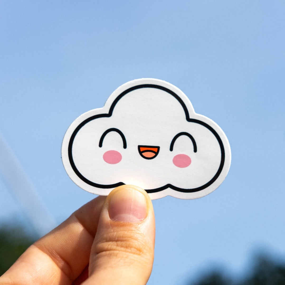Hand holding up white cloud with smiley face sticker