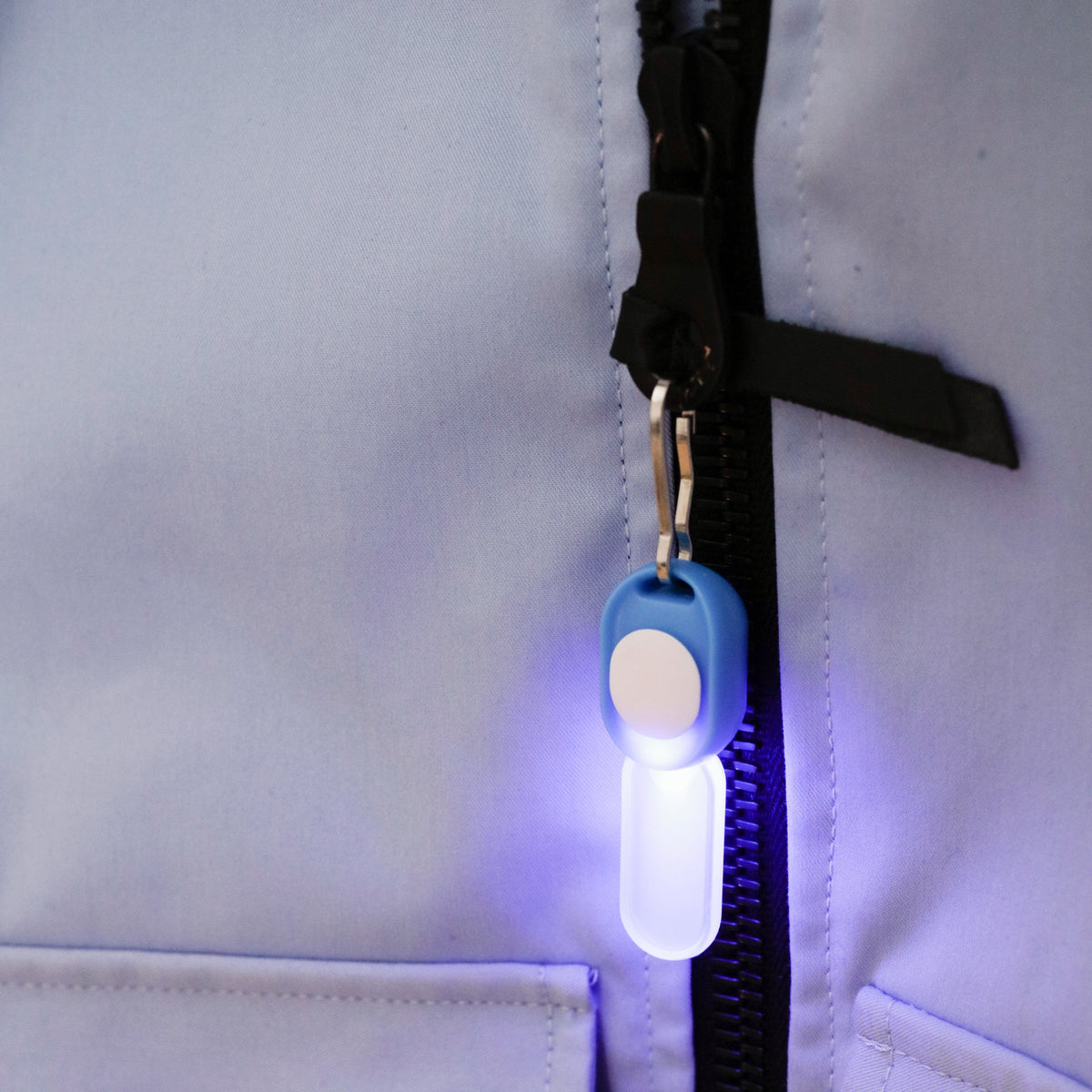 Light-up keychain attached to a zipper on a light-colored jacket