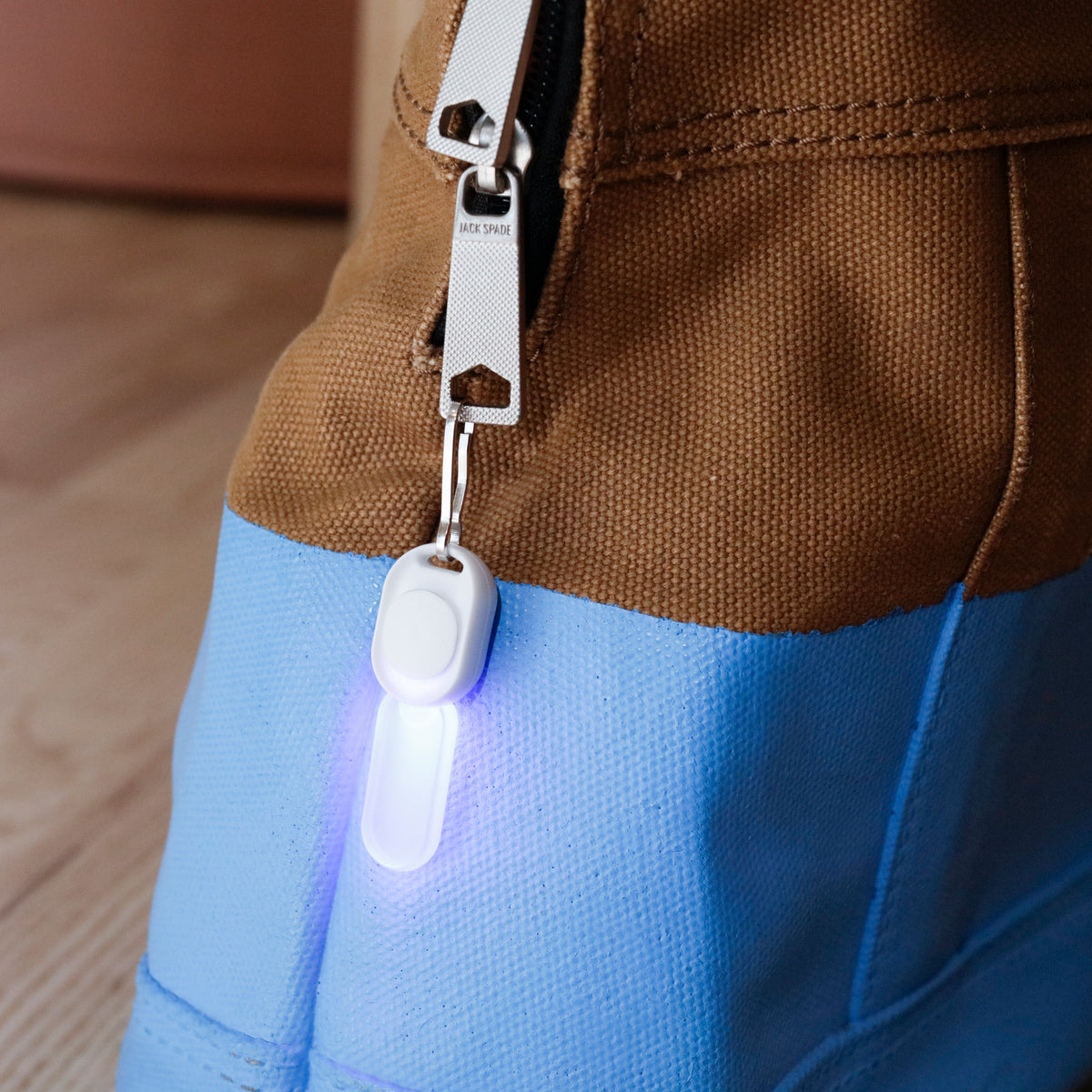 Light-up keychain attached to a brown jacket pocket