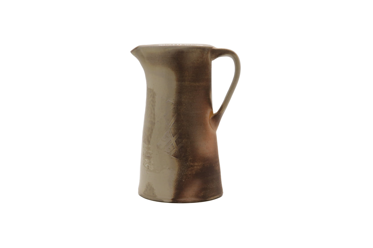 Ceramic pitcher with a brown glaze on a white background