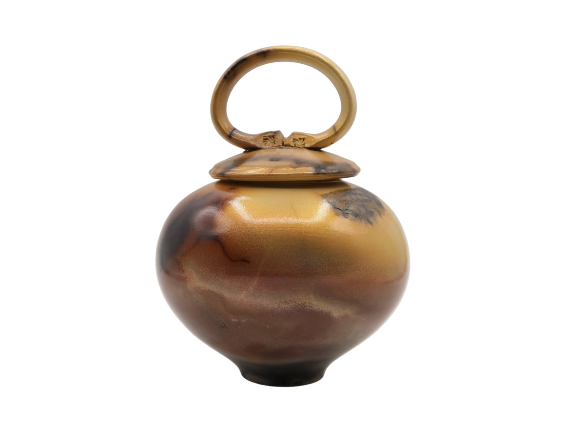 Ceramic pot with a gold lid on a white background