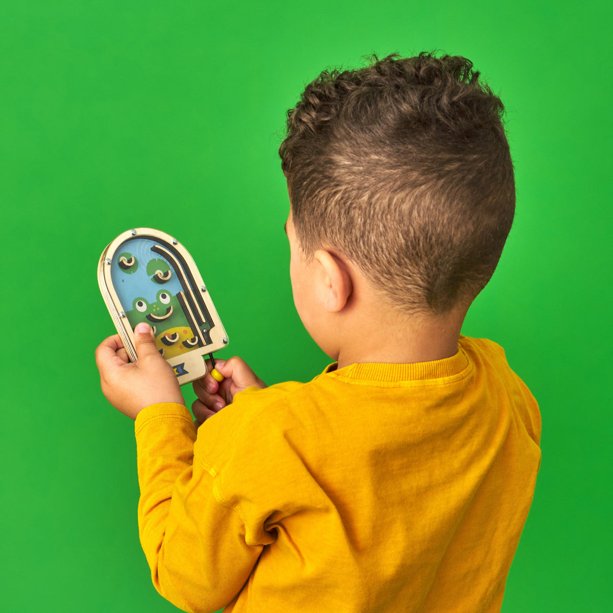 Child holding a toy game with a green screen background