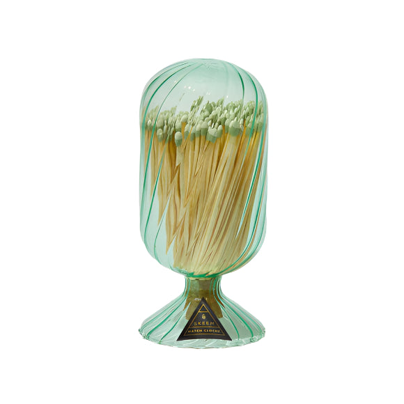 Green glass container with matches in it on a white background