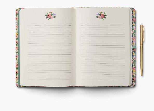Open notebook with floral design on cover and pen on white background