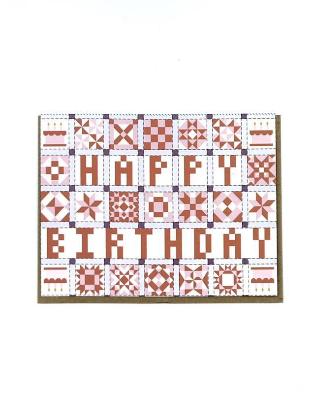 Greeting card with a pink, white, and grey patchwork quilt design and the words 'HAPPY BIRTHDAY' across the front.