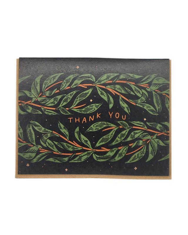 A folded greeting card with a floral design with black background and the words 'THANK YOU' in the center.