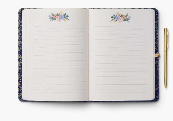 Open notebook with floral designs on the top of the lined pages with a pen on a white background