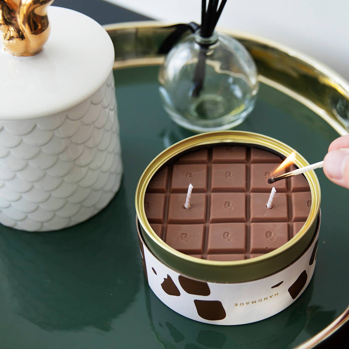 Candle shaped like a chocolate bar being lit on a decorative tray.