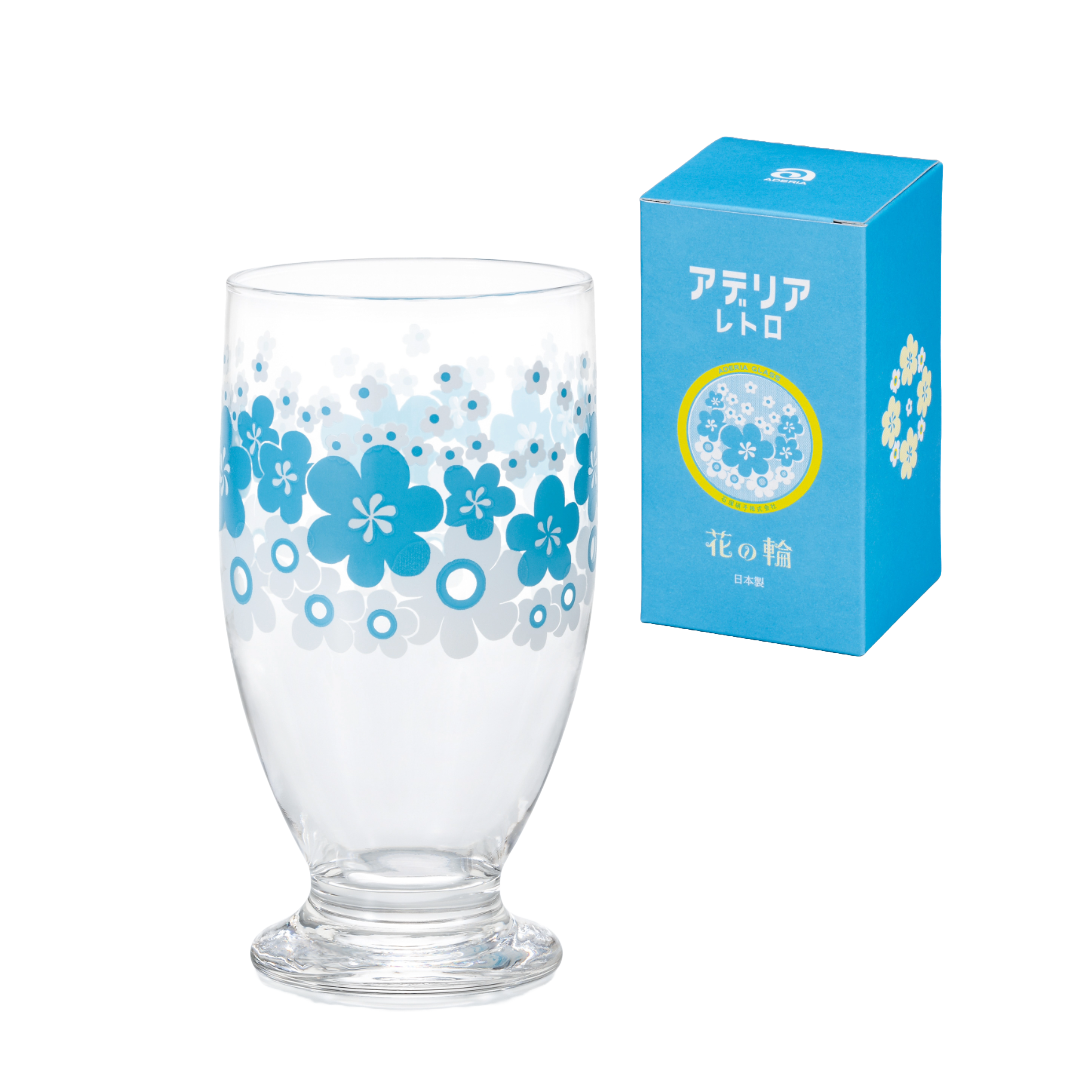 Clear glass with blue floral design next to its packaging on a white background