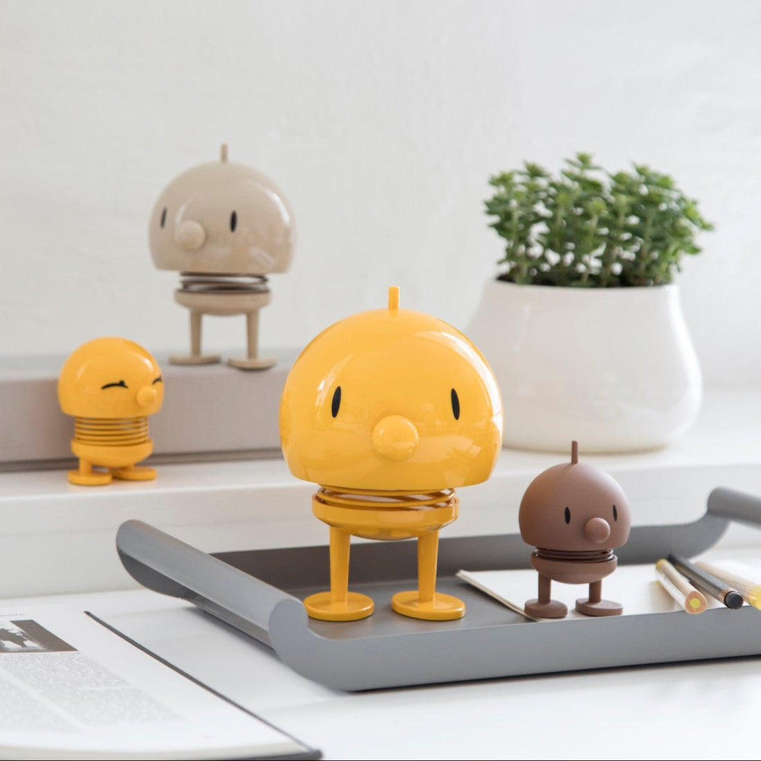 Yellow character figurine on a desk with a plant and other small items in the background