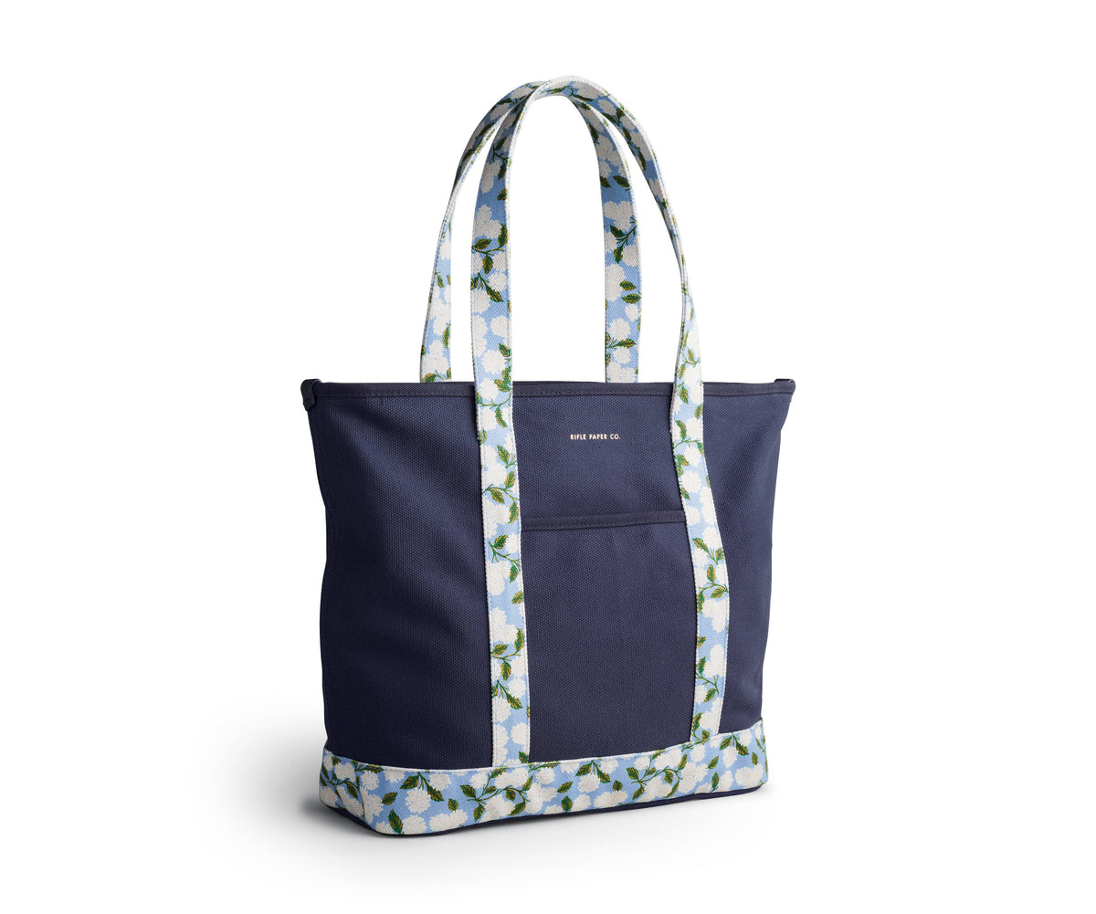 Side view of navy tote bag with floral-patterned handles on a white background