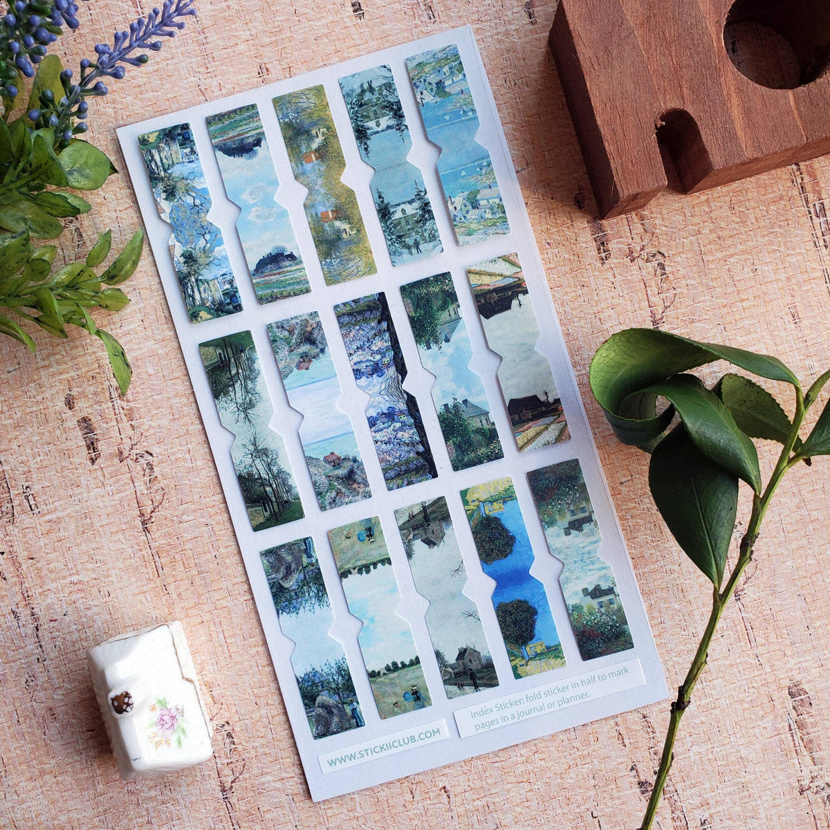 Sheet of scenic stickers on a wooden surface with plants around