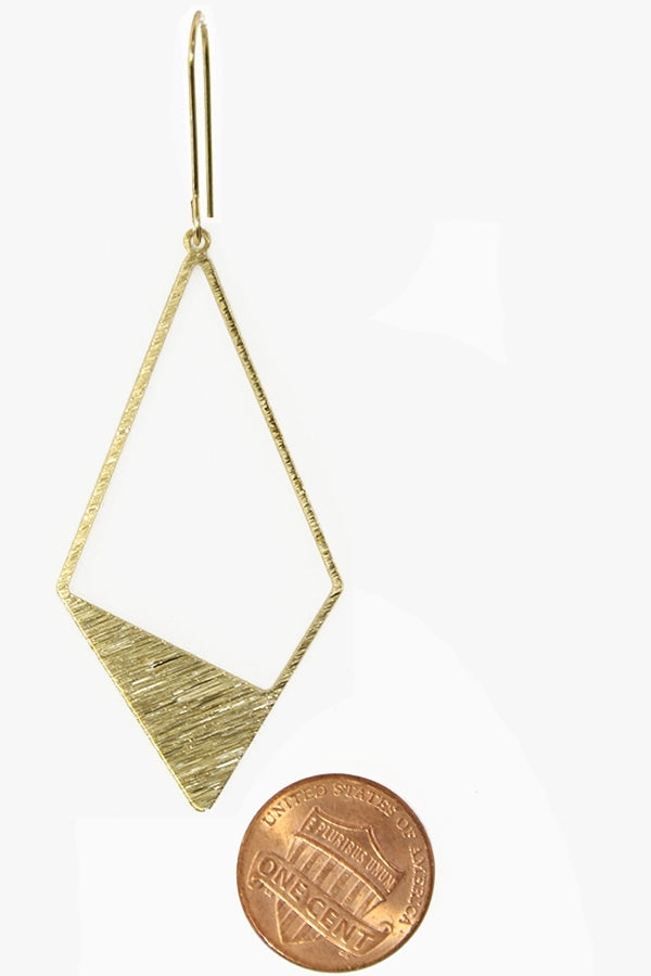Gold geometric earring next to a penny for scale on a white background