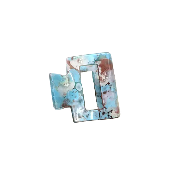 Blue decorative hair clip with a marbled design on a white surface