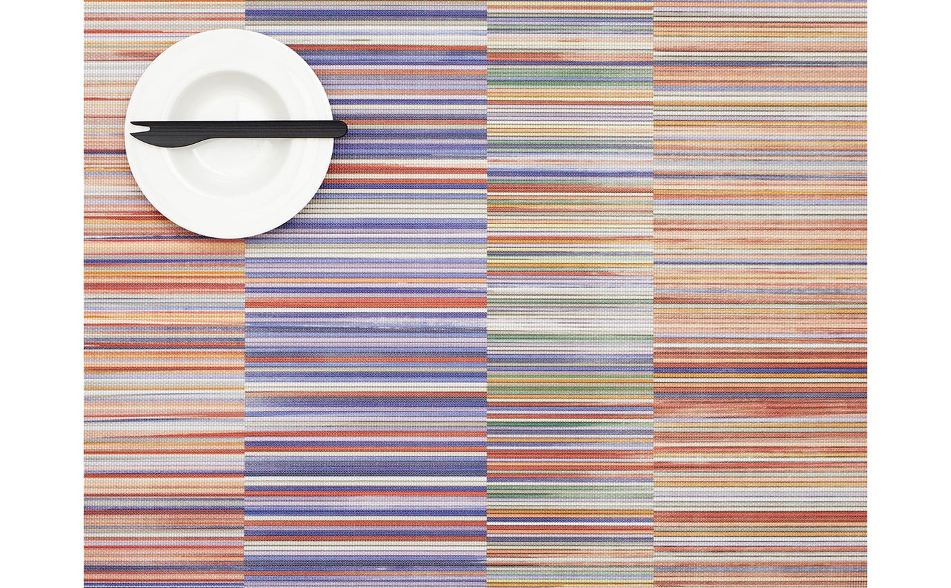 Colorful striped placemat with a white plate and black knife on a white background